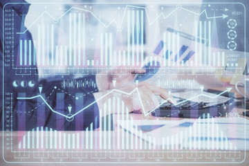 Double exposure of graph with man typing on computer in office on background. Concept of hard work. Closeup.