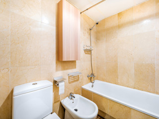Clean bright bathroom interior with white toilet and marble tiles. Original designed hotel space with modern pieces