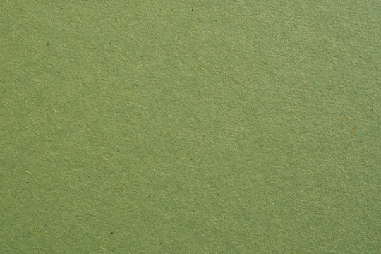 The surface of a sheet of green cardboard. Background or wallpaper. Rough paper texture with cellulose fibers. View from above. Macro