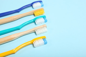 natural bamboo toothbrushes and plastic on a colored background top view.