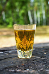 glass of whiskey on a table in a forest