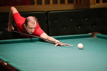 Fototapeta premium the player takes aim at the ball in Billiards