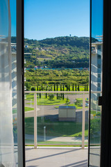 View of the green hills through the open glass door of the balcony.