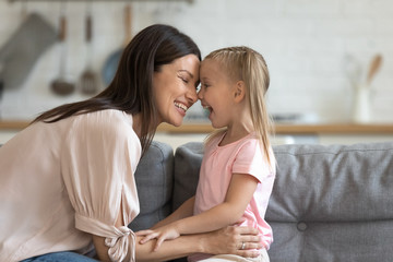 Happy mother having fun with cute kid daughter on sofa