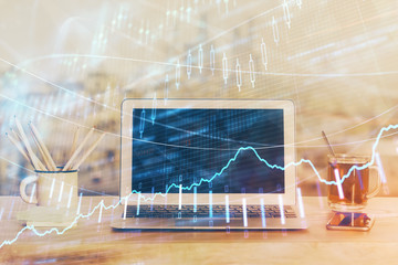 Stock market graph on background with desk and personal computer. Double exposure. Concept of financial analysis.