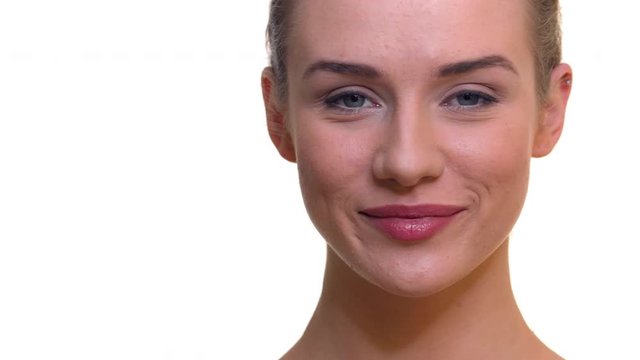 Close up of woman smiling on the camera. Face of Caucasian or European lady as she smiles looking in the front on isolated white background inside a studio ideal for skin or health care mock up