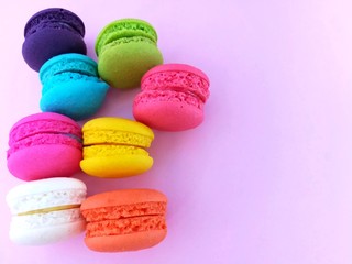 Fototapeta na wymiar Delicious macaron sweets arranged on left,  colorful macaroon on pink background