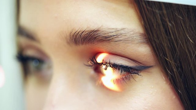 Eyes examination. Close-up woman's eyes checking by a doctor. Laser shining inside the eye. Eyesight concept.