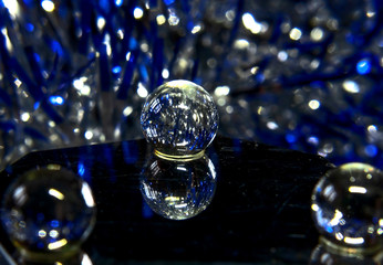 Macrophoto - a glass transparent ball on a mirror surface photographed in close-up under dim lighting, abstract background