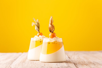 Elegant dessert jelly with passion fruit and physalis on yellow background, gourmet food concept