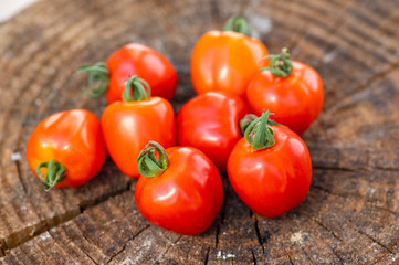 Group of ripened tasty red raw strawberry tomatoes on wood on green natural background, tasty healthy vegetables still life