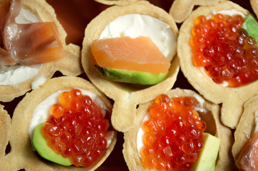 tartlets with red salmon caviar, slices of fresh salmon, cheese, avocado and tomatoes