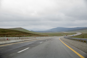road receding into the distance in open countryside under a cloudy white sky with focus to the...