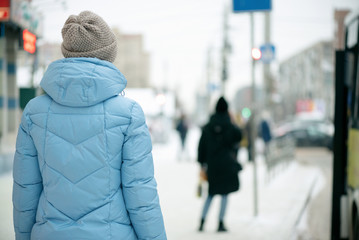 Woman waiting a bus on the bus stop in winter.