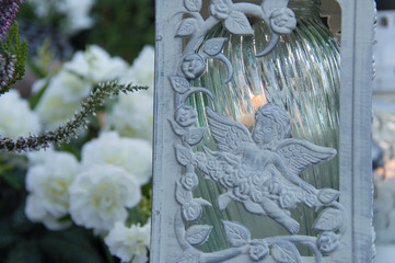 Monument and candles in the cemetery. All Saints Day in Poland. Icon lamp with angels.