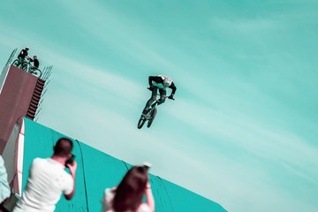 Extreme unrecognizable cyclist, young man doing jump with bmx bike on background of sky....