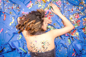 young sleeping woman lying face down on floor among sequin. Fatigue from a stormy party concept.