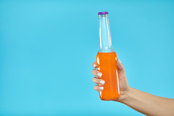 Female hand holding Bottle of alcohol beverage on a yellow background