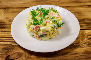 Salad with crab sticks, sweet corn, cucumber, eggs and mayonnaise on wooden table