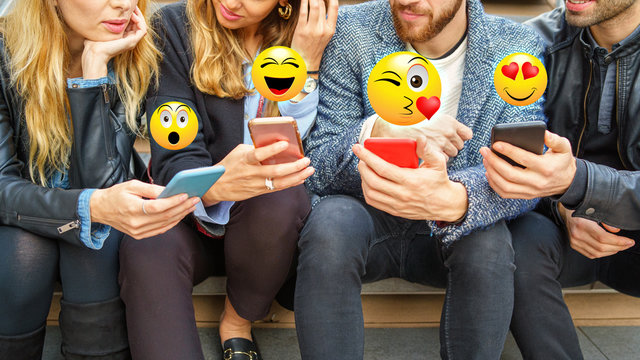 Close Up On People Hands Using Smartphones With Overlay Of Emoji Faces. Young People Using Internet And Social Networks  Application Concept.