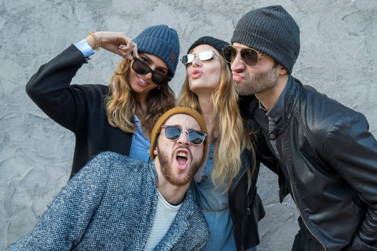 Funky and trendy fashion group of people wearing winter hat and sunglasses making weird grimace faces.