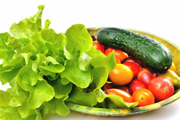 lettuce yellow and red tomatoes, cherry tomatoes and cucumber on a vintage dish white background, isolate, top view