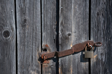 Detail of a rusty padlock at weathered wooden planks