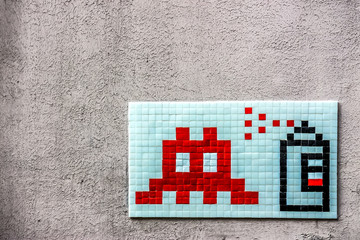 a graffiti mosaic depicting a spray can and an icon of space invaders on a wall of paris - obrazy, fototapety, plakaty