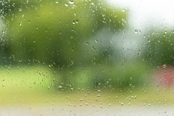 View through a window with raindrops, unsharp colours in the background