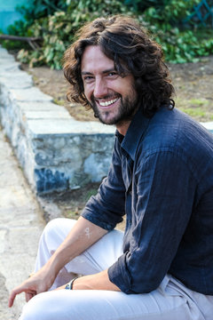 handsome italian young man with long, wavy hair, brown eyes, smile