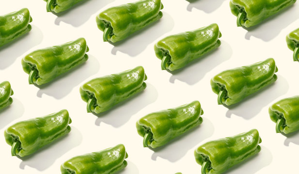 From above creative composition of sliced green whole pepper on white surface