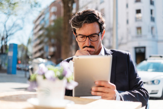 Elderly Man Using Gadget While Relaxing At Cafe