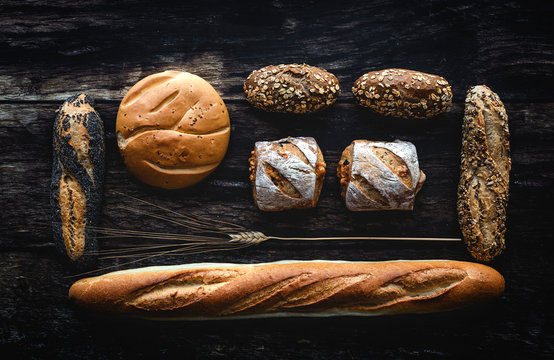 Gold assortment bread homemade on dark wood background, captured from above top view, flat lay in knolling concept