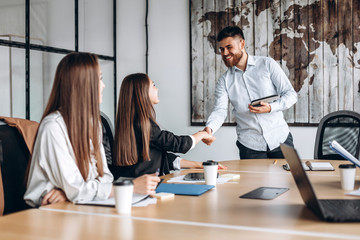 Attractive guy with a beard shakes hands with the girl he works with in the office