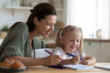 Babysitter mom teaching kid girl drawing with felt pen together