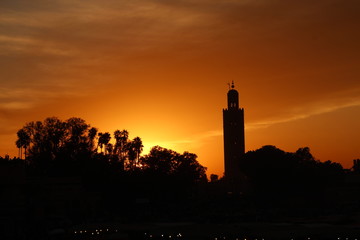 Orange sunset in the tower of the Marrakech square from a terrace and the sun in the background. Morocco