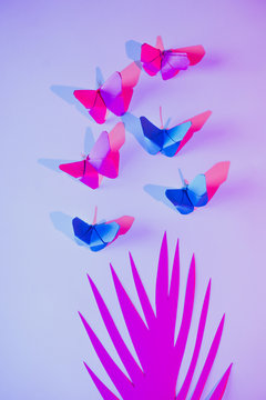 Pink and blue butterflies attached to lilac wall over carved paper leaf