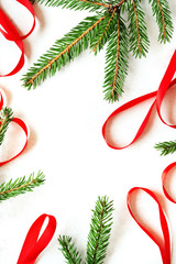 Christmas decoration with fir branches and red ribbons on white concrete background. Top view with copy space.