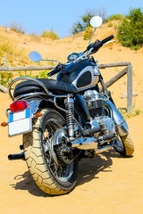 classic motorcycle with blank plate parked near a sand dune on the beach, Sardinia, Italy