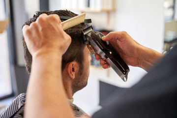 Stock photo of a detail of the hands of a barber cutting hair with a comb and a razor. Barbershop and lifestyle