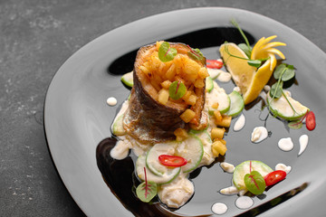 Grilled trout fillet with vegetables, on black background