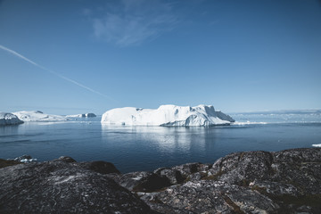 Arctic nature landscape with icebergs in Greenland icefjord with midnight sun sunset sunrise in the horizon. Early morning summer alpenglow during midnight season. Ilulissat, West Greenland. © Mathias