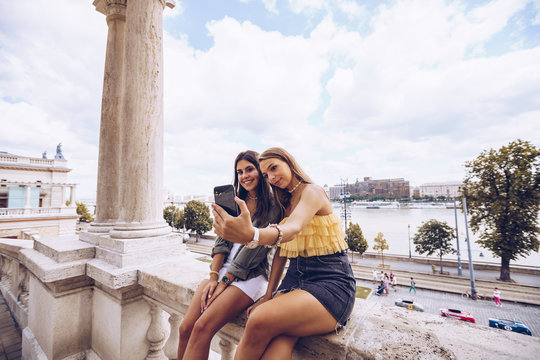 Laughing women taking selfie on old building
