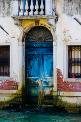 very ruined blue door bathed by the high water of the Venice lagoon, Italy