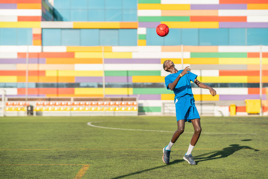 Skinny black teenager jugging football ball on head