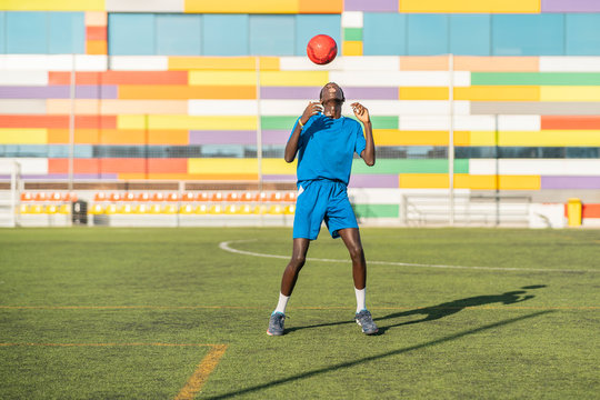 Skinny black teenager jugging football ball on head