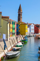 Fototapeta na wymiar Water canal full of moored boats and multicolored houses in Burano, Venice, Italy