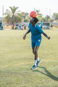 Skinny black teenager jugging football ball on head