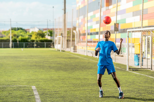 Skinny black teenager jugging football ball on head