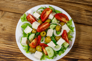 Greek salad with fresh vegetables, feta cheese and green olives on wooden table. Top view